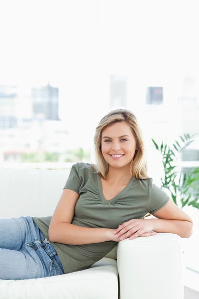 Kvinna över soffan, armar på armstödet, leende och — Stockfoto