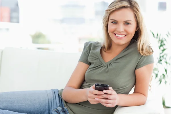 Mujer sonriendo y mirando delante de ella mientras usa su teléfono — Foto de Stock