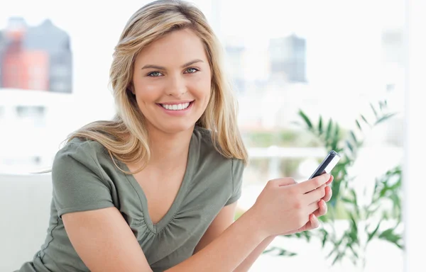 Frau freut sich lächelnd, als sie ihr Telefon in der Hand hält — Stockfoto