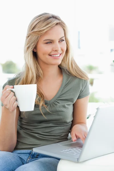 Woman looking slightly to the side, as she holds a cup in her ha — Stock Photo, Image