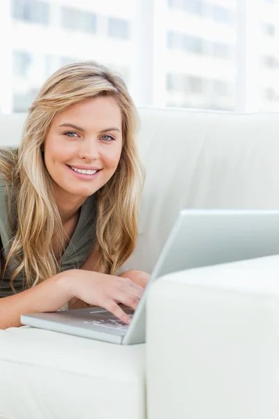Крупним планом, жінка посміхається, коли вона дивиться вперед, використовуючи свій ноутбук — стокове фото