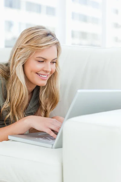 Close-up, vrouw op de Bank, met behulp van haar laptop en glimlachen — Stockfoto