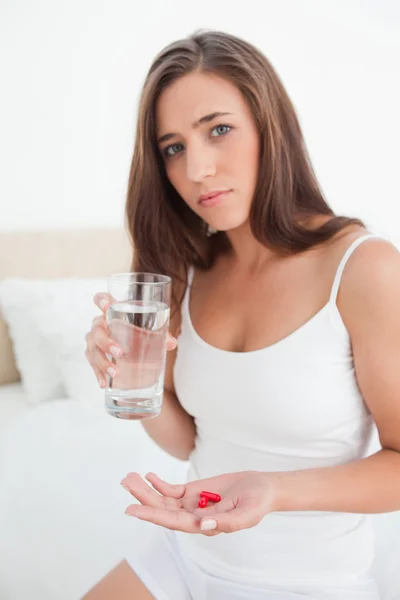 Женщина с таблетками в одной руке и стаканом воды в другой! — стоковое фото