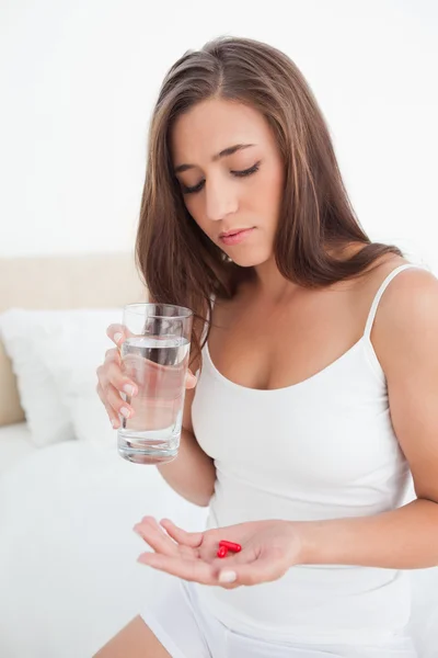 Woman looking down at the two pills she is going to take with wa — Stock Photo, Image