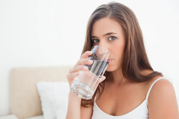 Woman looking forward drinking from a glass of water — Stock Photo, Image