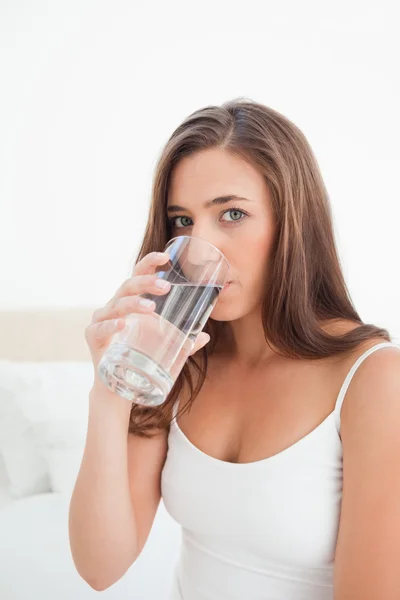 Close up, woman taking a drink from a glass while looking forwar — Stock Photo, Image