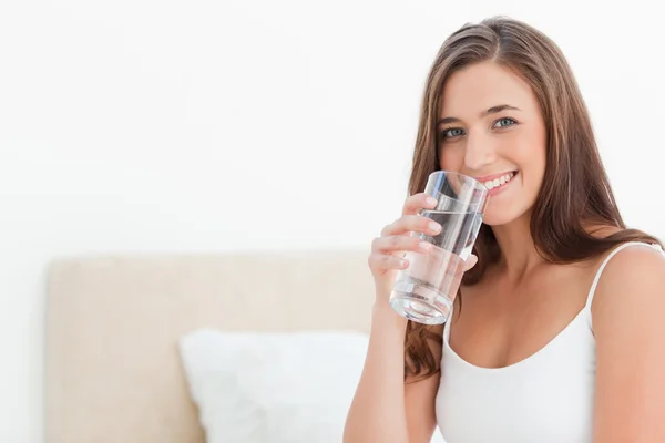 Woman smiles as she holds a glass to her mouth — Stock Photo, Image