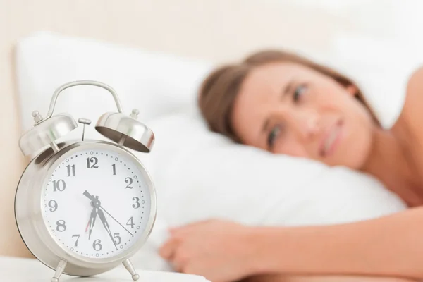 Frau im Bett mit Wecker neben ihr, der die Uhrzeit anzeigt — Stockfoto