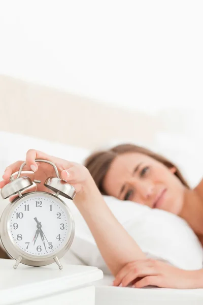 Woman silencing her alarm clock with her hand — Stock Photo, Image