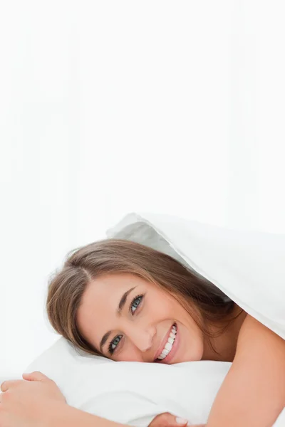 Vertical shot, woman in bed, awake, smiling while looking ahead — Stock Photo, Image