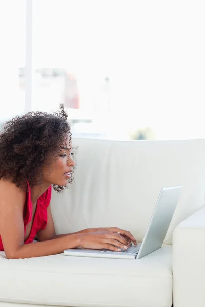 Kanepeye, kadın bakarak ve onu laptop kullanma — Stok fotoğraf