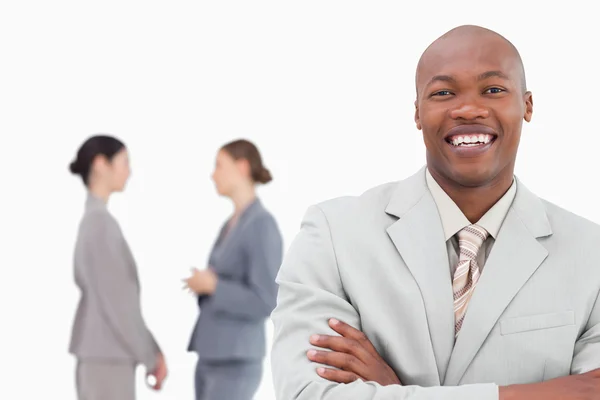 Smiling businessman with folded arms and co-workers behind him — Stock Photo, Image