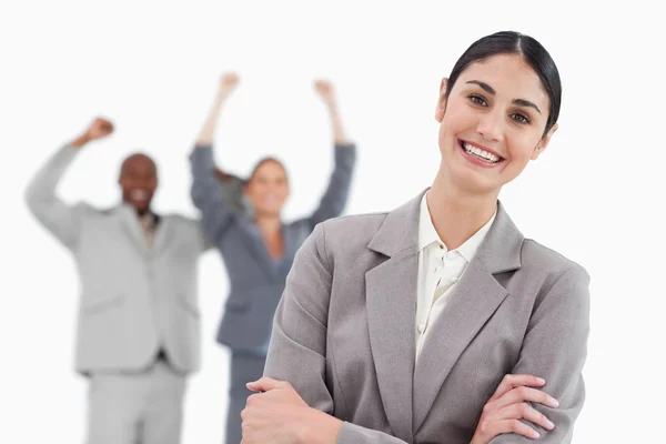 Smiling saleswoman with cheering co-workers behind her — Stock Photo, Image