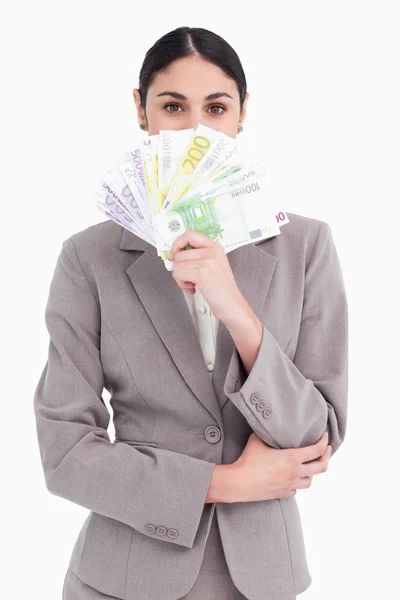 Jovem empresária escondendo o rosto atrás de notas bancárias — Fotografia de Stock