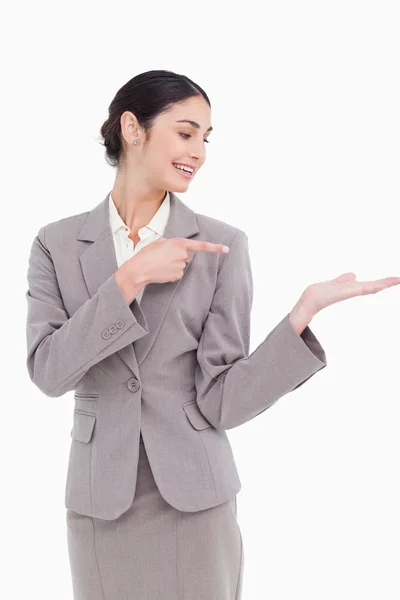 Empresária sorridente apontando para a palma da mão — Fotografia de Stock