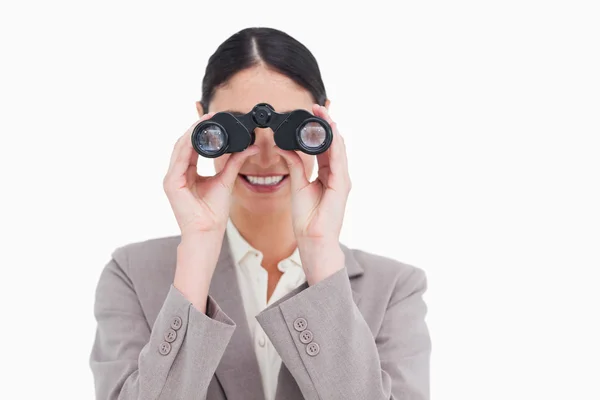 Smiling businesswoman looking through spy glasses — Stock Photo, Image