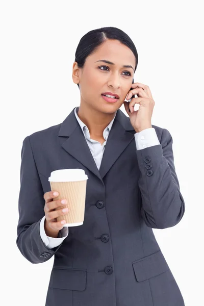 Close up of saleswoman with paper cup talking on cellphone — Stock Photo, Image