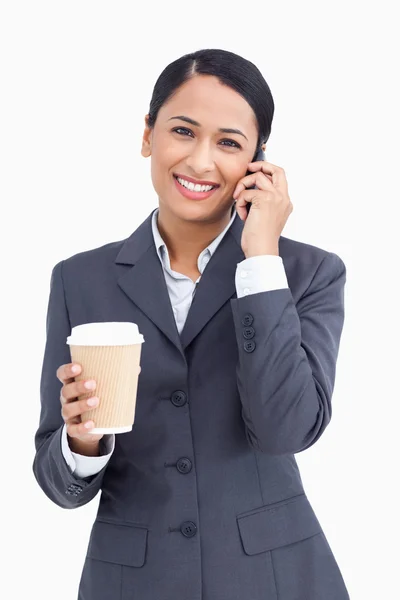 Primer plano de la vendedora sonriente con taza de papel y teléfono celular — Foto de Stock
