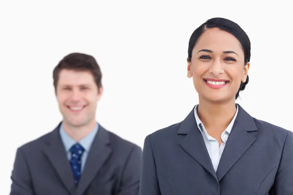 Close up of smiling saleswoman with colleague behind her — Stock Photo, Image