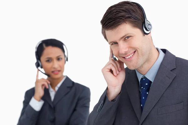 Close up of smiling call center agent with co-worker behind him — Stock Photo, Image