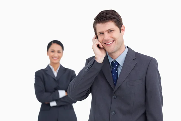 Κοντινό πλάνο χαμογελαστό πωλητής στο τηλέφωνο με τον συνάδελφό πίσω από — Φωτογραφία Αρχείου