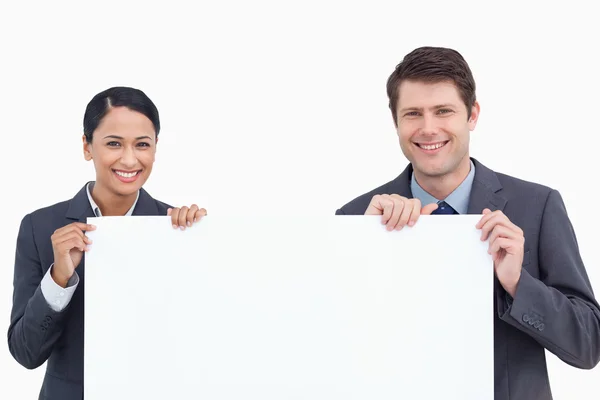 Close up of smiling salesteam holding blank sign — Stock Photo, Image