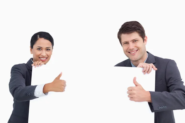 Close up of salesteam with blank sign giving thumbs up — Stock Photo, Image