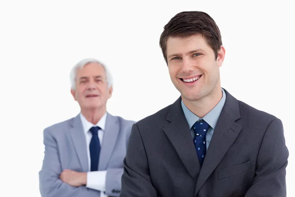Крупный план улыбающегося бизнесмена со своим боссом позади него — стоковое фото