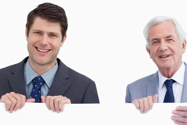 Primer plano de hombres de negocios sonrientes sosteniendo un cartel en blanco — Foto de Stock