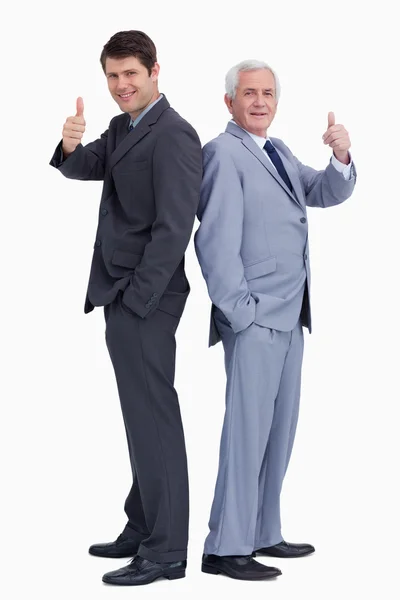 Businessmen standing back to back giving thumbs up — Stock Photo, Image