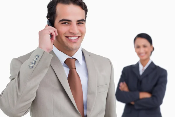 Salesman on his cellphone with colleague behind him — Stock Photo, Image