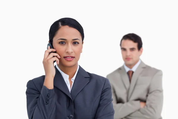 Saleswoman on her cellphone with colleague behind her — Stock Photo, Image