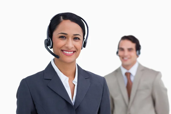 Smiling telephone support employee with colleague behind her — Stock Photo, Image