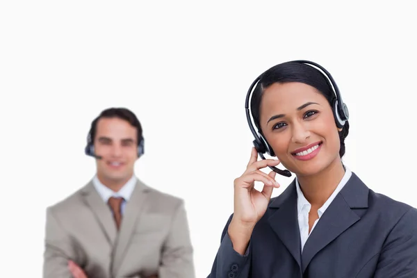 Smiling telephone support employee with co-worker behind her — Stock Photo, Image
