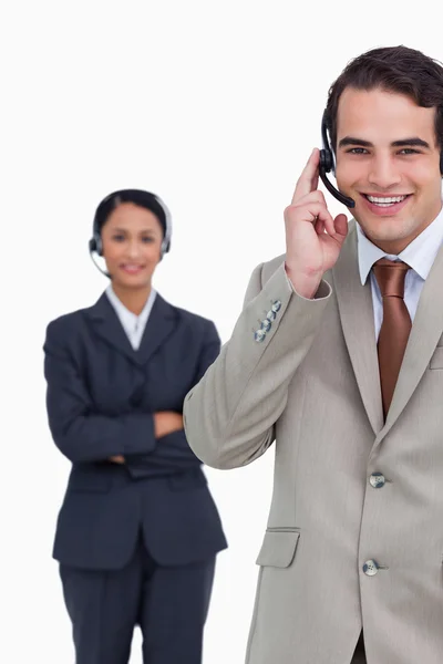 Un employé de hotline souriant avec un collègue derrière lui — Photo