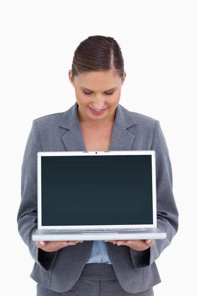 Улыбающаяся торговая женщина смотрит вниз на свой ноутбук — стоковое фото