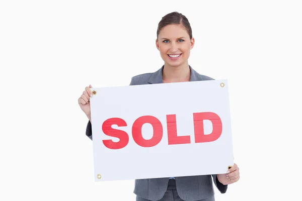Sonriente agente de bienes raíces que presenta signo vendido — Foto de Stock