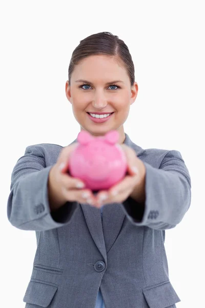 Smiling bank clerk offering piggy bank — Stock Photo, Image