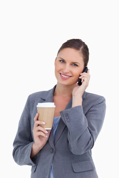 Усміхнена торгує жінка з паперовою чашкою на її мобільному телефоні — стокове фото