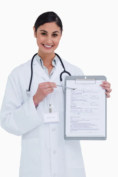 Uśmiechnięta kobieta lekarz wskazując w formie — Zdjęcie stockowe