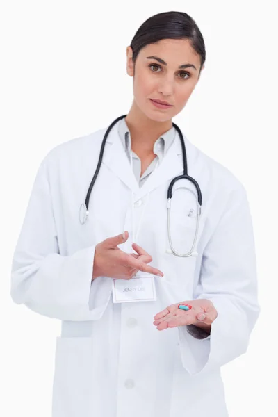 Female doctor pointing at pill in her hand — Stock Photo, Image