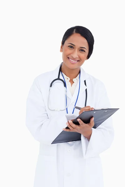 Close up of female physician taking notes on her clipboard — Stock Photo, Image
