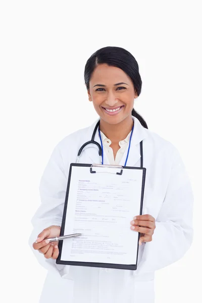 Bliska uśmiechający się kobiece kobieta lekarz wskazując w formie — Zdjęcie stockowe