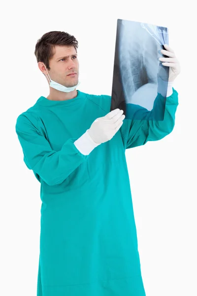 Close up of male doctor wearing scrubs looking at x-ray — Stock Photo, Image