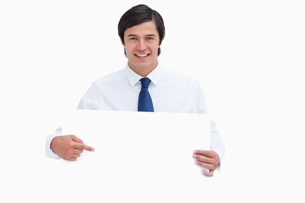 Smiling young tradesman pointing at blank sign in his hands — Stock Photo, Image