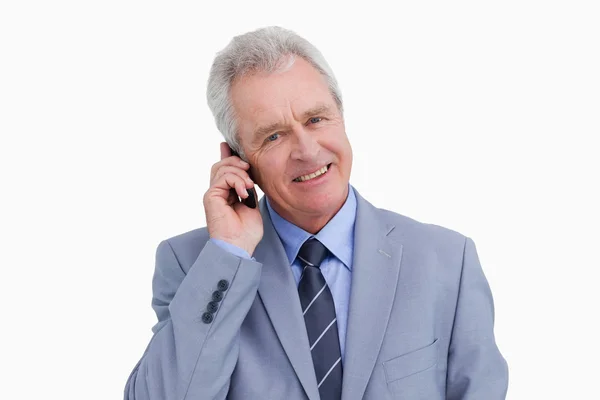 Zbliżenie uśmiechający się dojrzały przedsiębiorca na jego telefon komórkowy — Zdjęcie stockowe