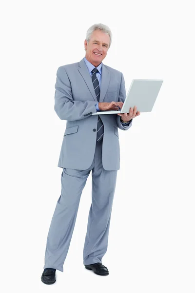Lachende volwassen handelaar met zijn laptop — Stockfoto