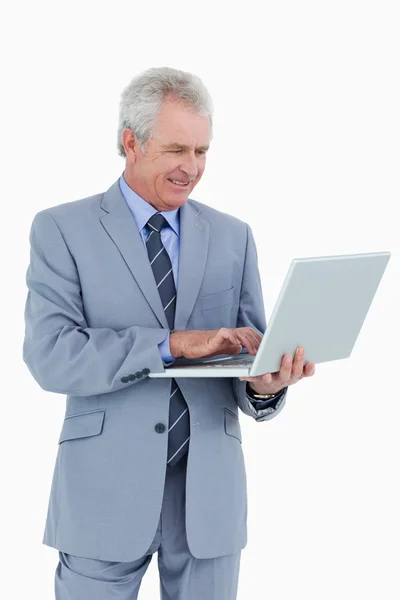 Улыбающийся взрослый торговец, работающий над своим ноутбуком — стоковое фото