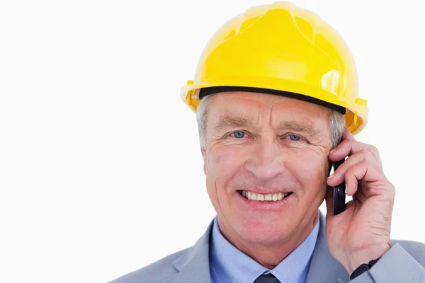 Sorrindo arquiteto maduro com capacete no telefone — Fotografia de Stock