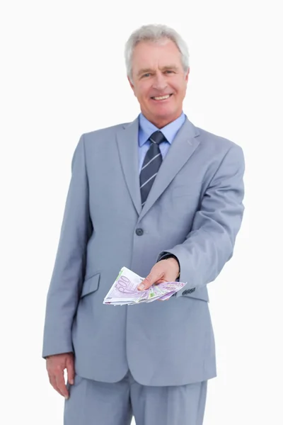 Marchand mature souriant tenant des billets de banque dans sa main — Photo